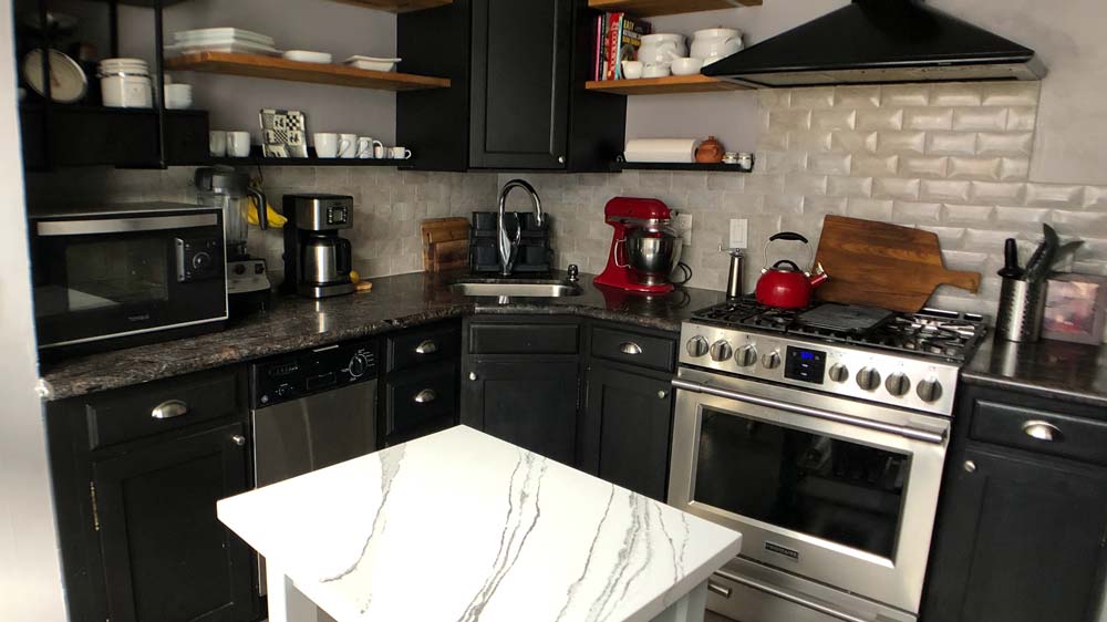 A kitchen wtih a stainless steel stove and vent hood